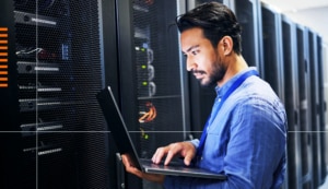 Man looking at computer near servers