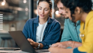 Group of three IT professionals looking together at a laptop screen